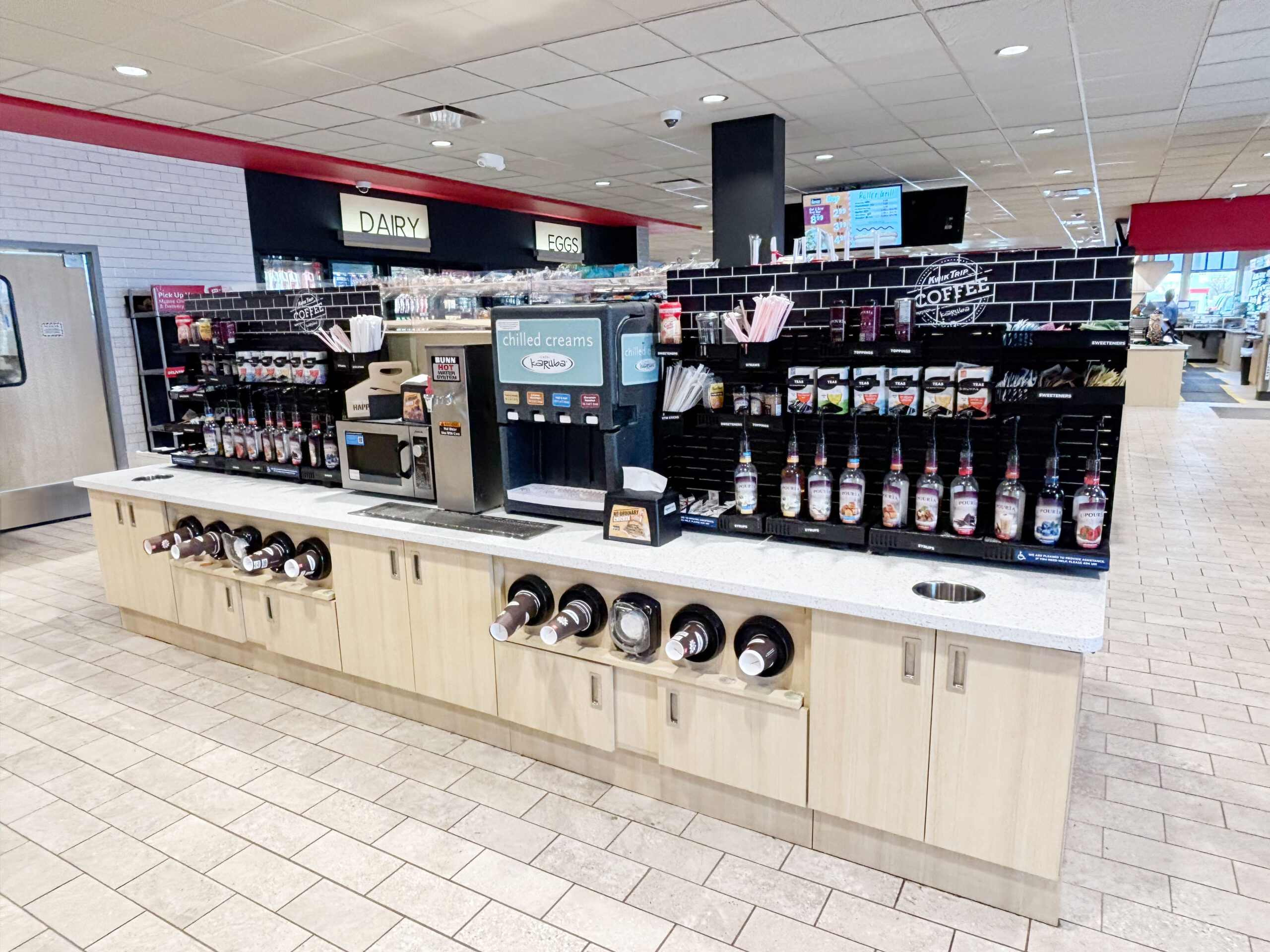 Convenience store coffee station with PanelRak merchandising system organizing syrups, lids, and condiments for improved visibility and customer flow